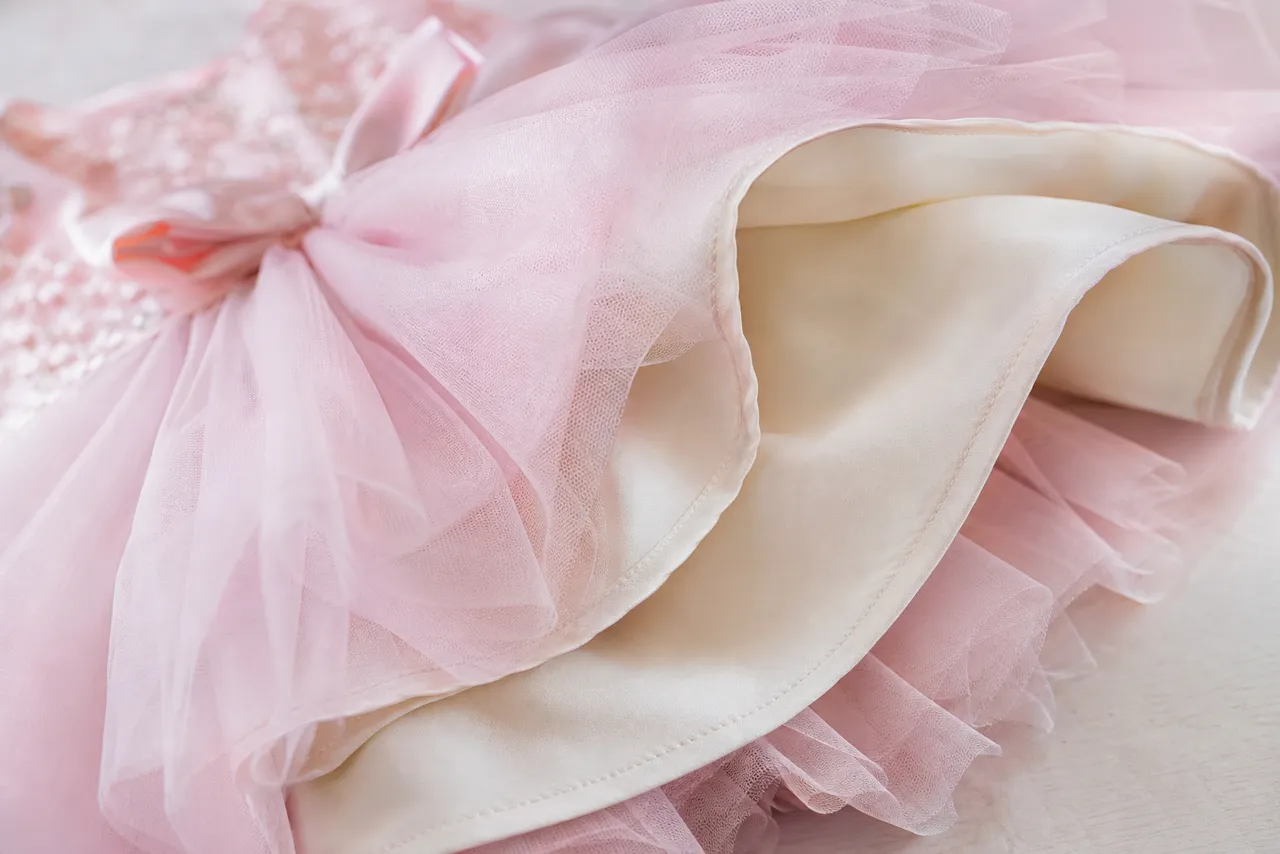 Detalhe de tule, forro macio, laço e acabamento de vestido infantil para festa