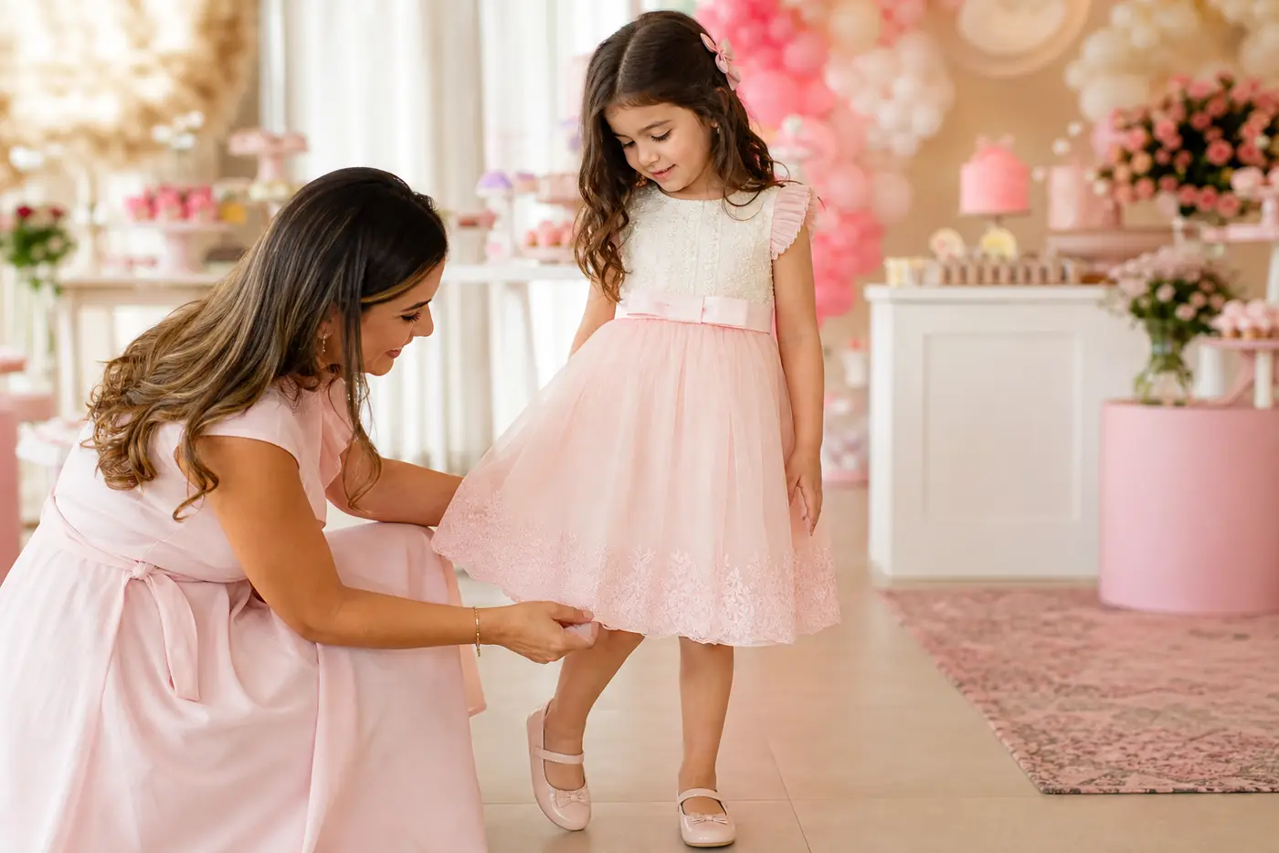 Menina com look infantil feminino de aniversário enquanto a mãe confere caimento e conforto