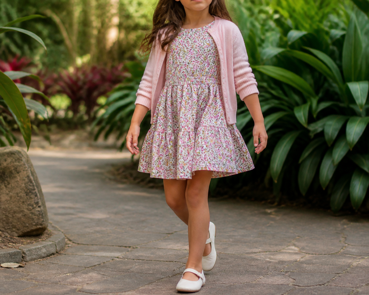 Menina usando vestido floral infantil com cardigan leve em jardim
